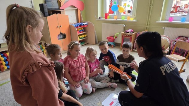 zdjęcie przedstawia grupę przedszkolaków i funkcjonariuszkę policji. 