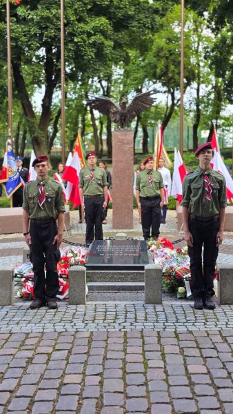 Zdjęcie przedstawia 4 harcerzy stojących na baczność przy pomniku