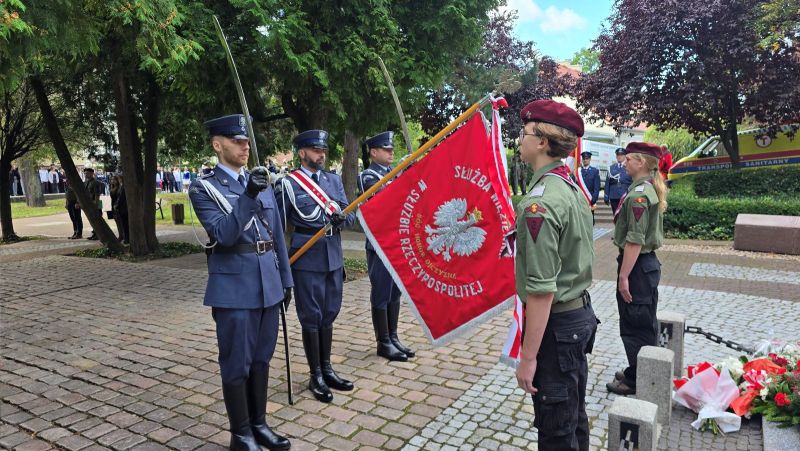 Zdjęcie przedstawia delegację  3 mężczyzn ze służby więziennej, ze sztandarem, stoją przed pomnikiem