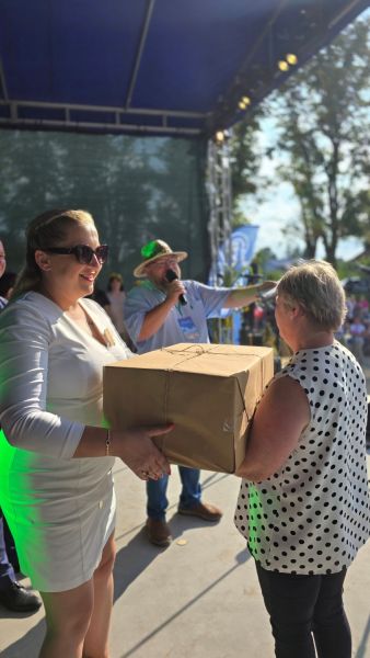 Wójt Gminy Gardeja wręcza kobiecie dużą paczkę owiniętą szarym papierem.