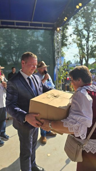 Starosta Powiatu Kwidzyńskiego wręcza kobiecie dużą paczkę owiniętą szarym papierem.
