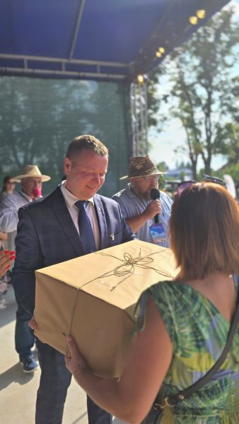 Starosta Powiatu Kwidzyńskiego wręcza kobiecie dużą paczkę owiniętą szarym papierem.