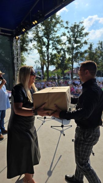 Członkini Zarządu Powiatu Kwidzyńskiego  wręcza mężczyźnie dużą paczkę owiniętą szarym papierem.