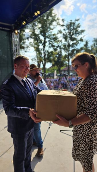 Starosta Powiatu Kwidzyńskiego wręcza kobiecie dużą paczkę owiniętą szarym papierem.