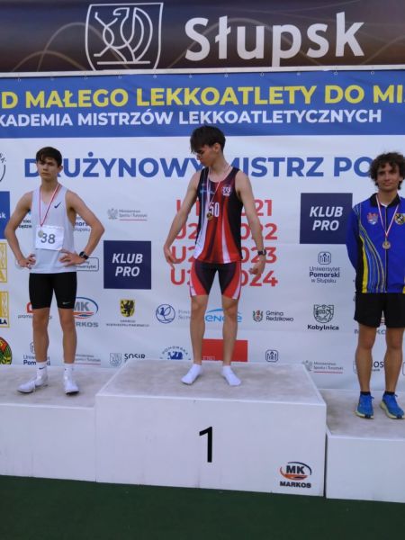 Aleksander Podlasiński, zawodnik, Kwidzyńskiego Klubu Lekkoatletycznego „Rodło”, wraz z innymi uczestnikami na podium.