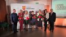 Na zdjęciu widać 5 nagrodzonych kobiet z kwiatami i listami gratulacyjnymi w towarzystwie dwóch mężczyzn, w tle ścianka Powiatu Kwidzyńskiego