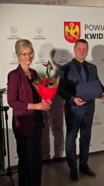 Na zdjęciu widać kobietę z kwiatami, obok starosta kwidzyński