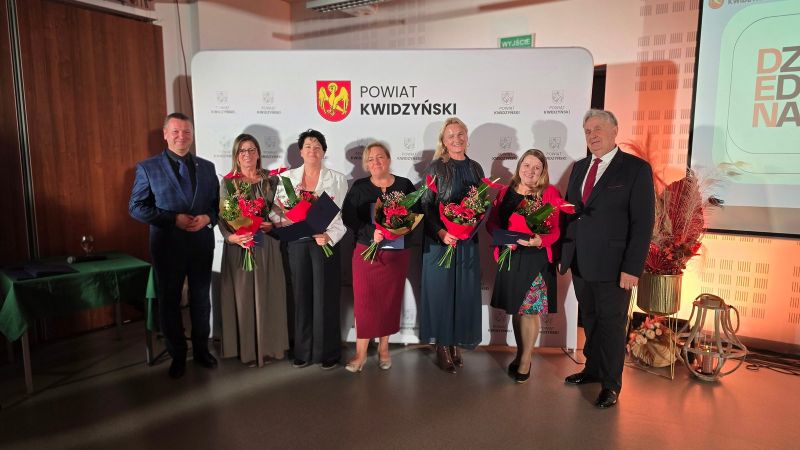 Na zdjęciu widać 5 nagrodzonych w towarzystwie dwóch mężczyzn, w tle ścianka Powiatu Kwidzyńskiego