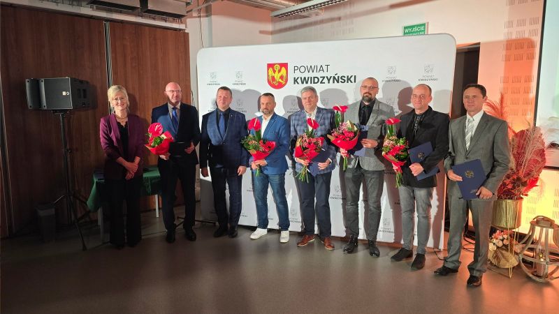 Na zdjęciu widać 4 nagrodzonych w towarzystwie dwóch mężczyzn, w tle ścianka Powiatu Kwidzyńskiego