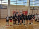 Zdjęcie przedstawia dziewięcioosobową grupę młodzieży. Wszyscy ubrani są w czarne koszulki i mają medale na szyjach. Za nimi stoją Tomasz Kazimierczyk, Karolina Nowak i Tomasz Frejnagiel. 