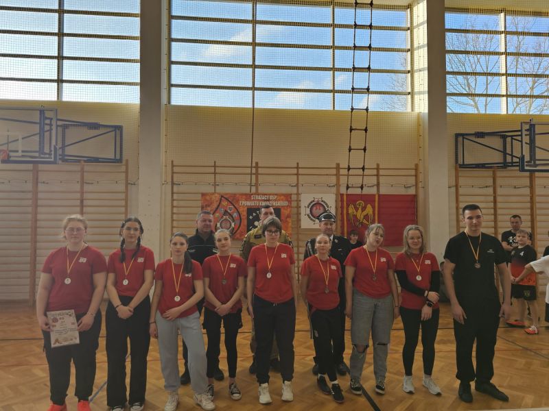 Zdjęcie przedstawia dziewięcioosobową grupę młodzieży, po wręczeniu medali.  Za nimi stoją Tomasz Frejnagiel, Piotra Sztypkę oraz Tomasza Kazimierczyka.