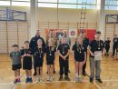 Zdjęcie przedstawia siedmioro dzieci stojących w rzędzie, po wręczeniu medali i dyplomów.  W tle kolejno Tomasz Frejnagiel, Damian Torbowski, Łukasz Szczepanowski oraz Tomasz Kazimierczyk.