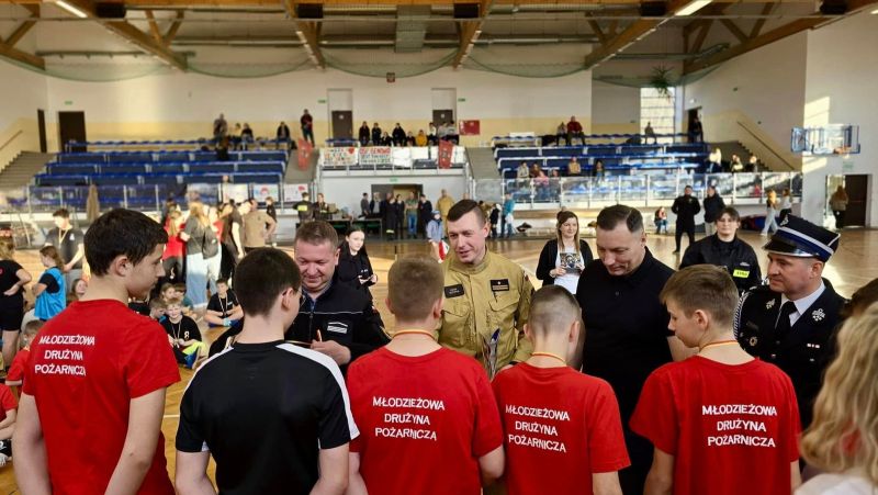 Zdjęcie przedstawia wręczanie nagród pięcioro chłopcom w koszulkach z napisem: młodzieżowa drużyna pożarnicza.Nagrody wręczane są przez Tomasza Frejnagiela, Piotra Sztypkę, Sebastiana Kasztelana oraz Tomasza Kazimierczyka.  