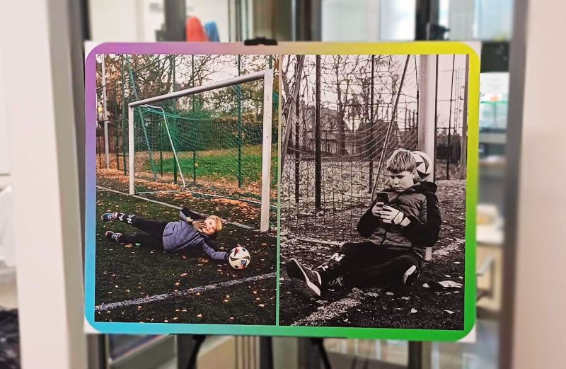 Lewa strona zdjęcia jest w kolorze i przedstawia uśmiechniętego chłopca broniącego bramki przed lecącą piłką. Prawa strona jest czarno – biała i przedstawia tego samego chłopca siedzącego przy bramce do piłki nożnej z telefonem w ręku.