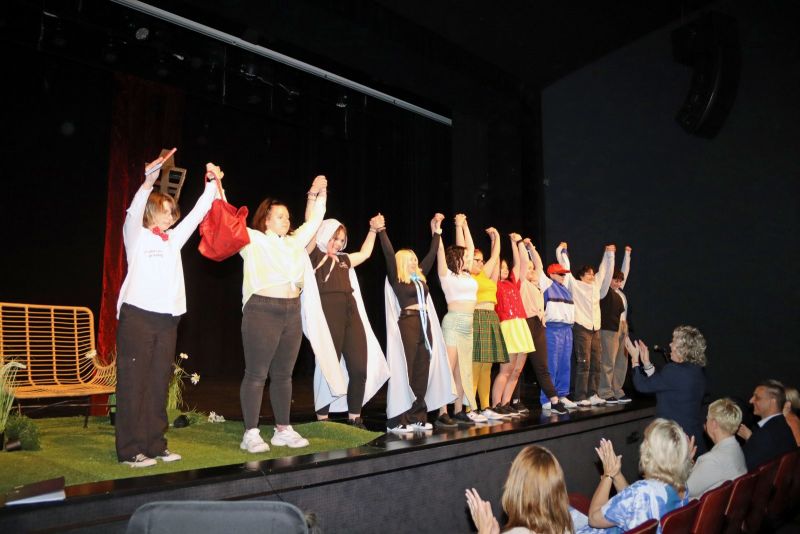 Uczestnicy wydarzenia kłaniają się ze sceny, a goście na widowni biją brawo.