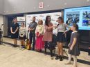zdjęcie przedstawia grupę ludzi, dzieci i osoby dorosłe. Jedna z nich trzyma w ręce gitarę, inna mikrofon. 