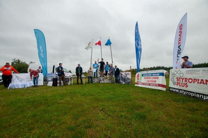 Na zdjęciu znajduje się grupa ludzi oraz trzy osoby stojące na podium.