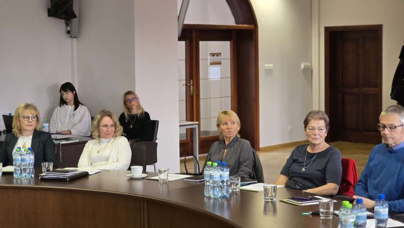 zdjęcie przedstawia grupę osób siedzących przy okrągłym stole podczas spotkania