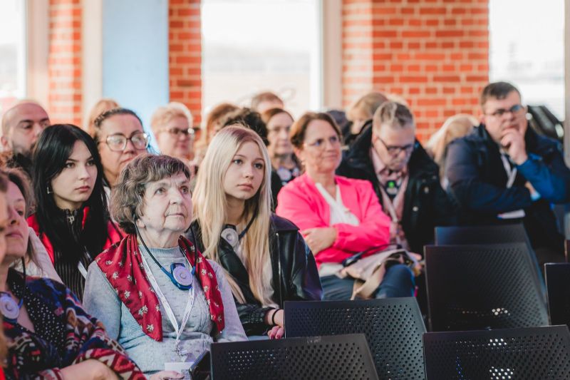 przedstawia grupę ludzi podczas konferencji. 