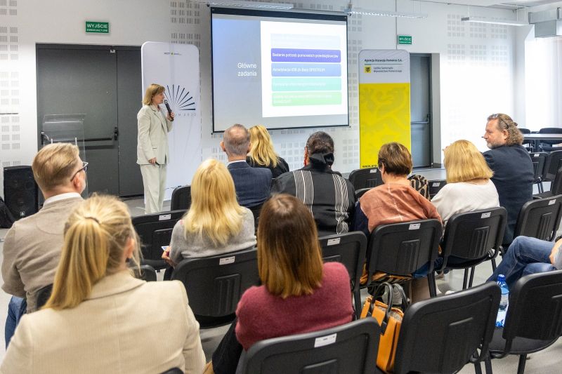 zdjęcie przedstawia osobę prowadzącą i uczestników konferencji.