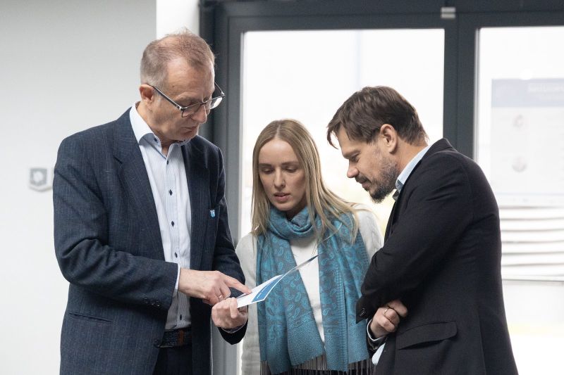 zdjęcie przedstawia trzy osoby, patrzące w stronę dokumentu. 