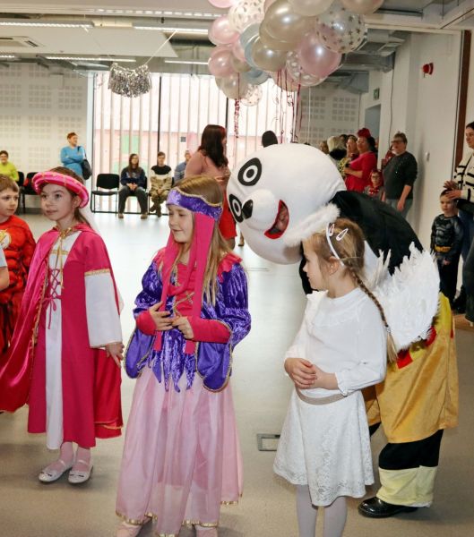 Animatorzy bawią się z dziećmi, które pełne entuzjazmu biorą udział w karnawałowych zabawach.