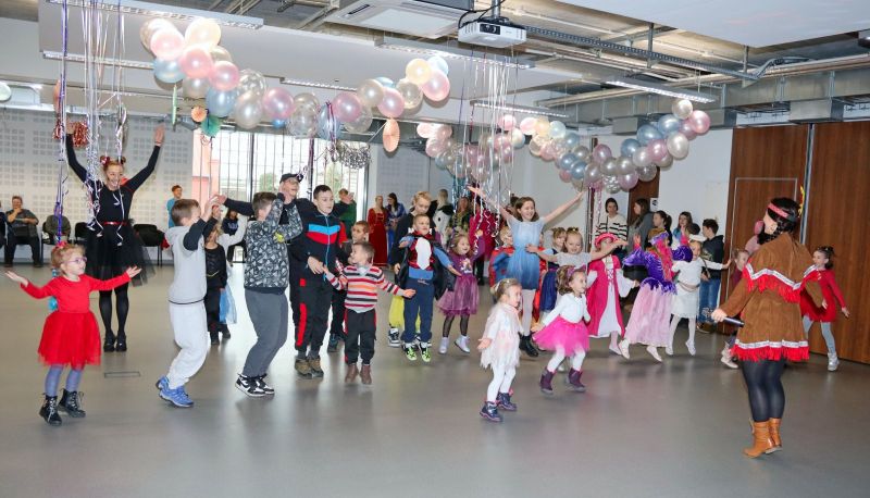 Dzieci i animatorzy wspólnie bawią się w rytm muzyki, ciesząc się karnawałowym szaleństwem.