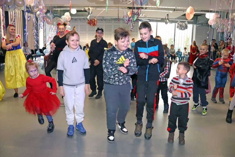 Animatorzy bawią się z dziećmi, które radośnie uczestniczą w karnawałowych zabawach.