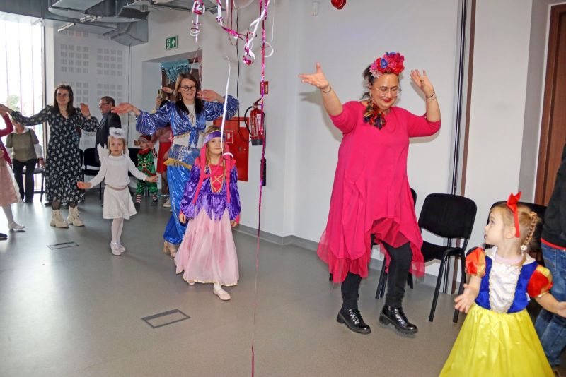 Dzieci śmieją się i bawią w towarzystwie animatorów, angażując się w kreatywne zabawy.