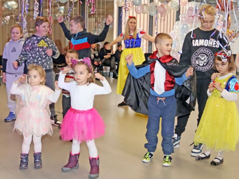 Dzieci tańczą wesoło w rytm muzyki, ciesząc się karnawałową zabawą.