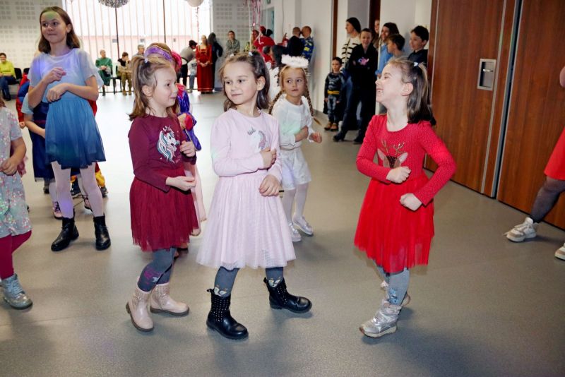 Dzieci tańczą, skacząc w rytm muzyki, pełne energii i radości podczas balu karnawałowego.