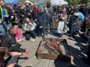 zdjęcie przedstawia grupę ludzi, smażących kiełbasy. 