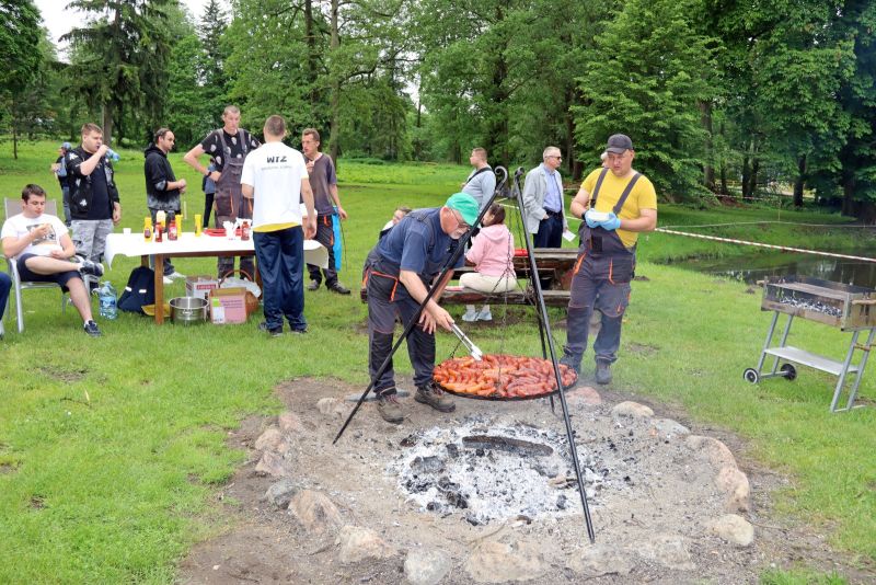 Plenerowy poczęstunek dla uczestników spartakiady. W tle ognisko i grill. 