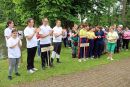 Drużyny biorące udział w spartakiadzie stoją razem na terenie parku. Uczestnicy ubrani w sportowe stroje.