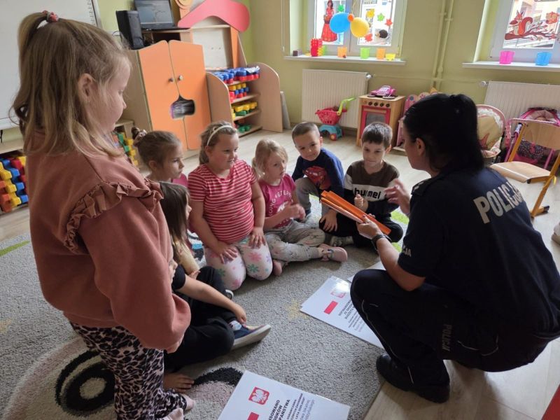 zdjęcie przedstawia grupę przedszkolaków i funkcjonariuszkę policji. 
