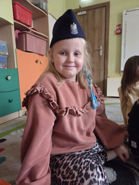 zdjęcie przedstawia dziewczynkę w policyjnej czapce. 