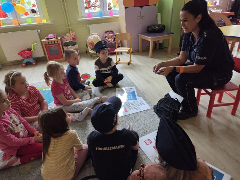 zdjęcie przedstawia grupę przedszkolaków i funkcjonariuszkę policji.