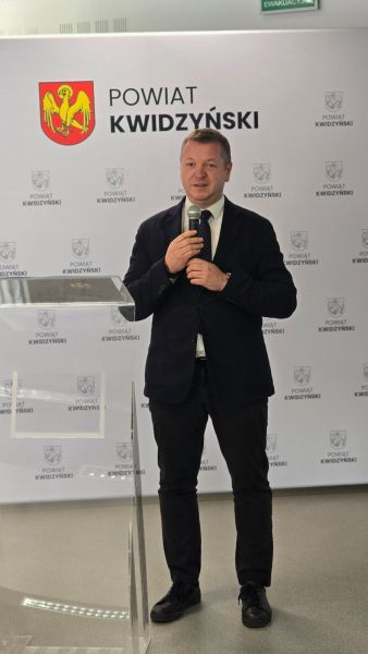Na zdjęciu widać przemawiającego do mikrofonu starostę kwidzyńskiego na tle ścianki powiatu kwidzyńskiego