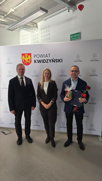 Na zdjęciu widać starostę kwidzyńskiego, kobietę i mężczyznę pozujących na tle ścianki powiatu kwidzyńskiego Na zdjęciu widać starostę kwidzyńskiego, kobietę i mężczyznę pozujących na tle ścianki powiatu kwidzyńskiego