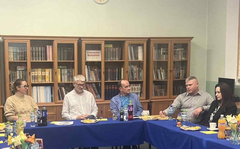 zdjęcie przedstawia trzech mężczyzn oraz dwie kobiety siedzące przy stole podczas dyskusji