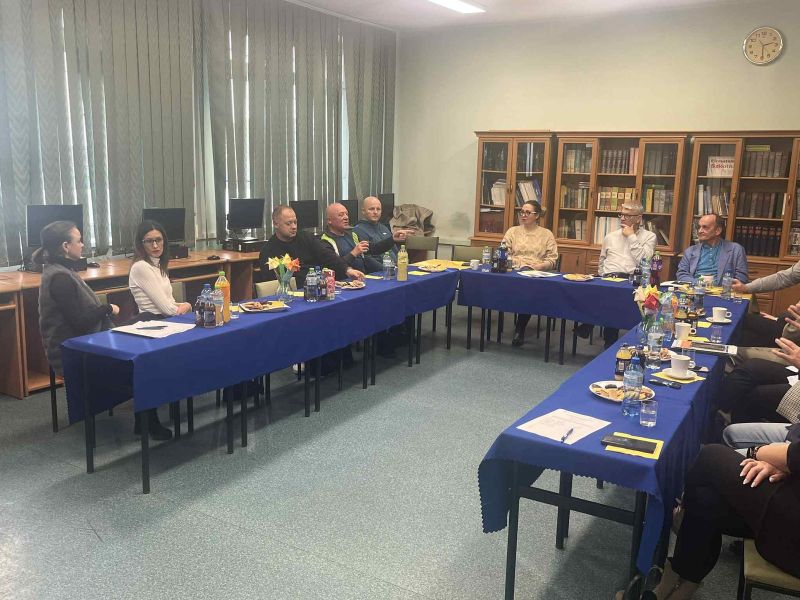 zdjęcie przedstawia grupę osób siedzącą przy stole podczas dyskusji