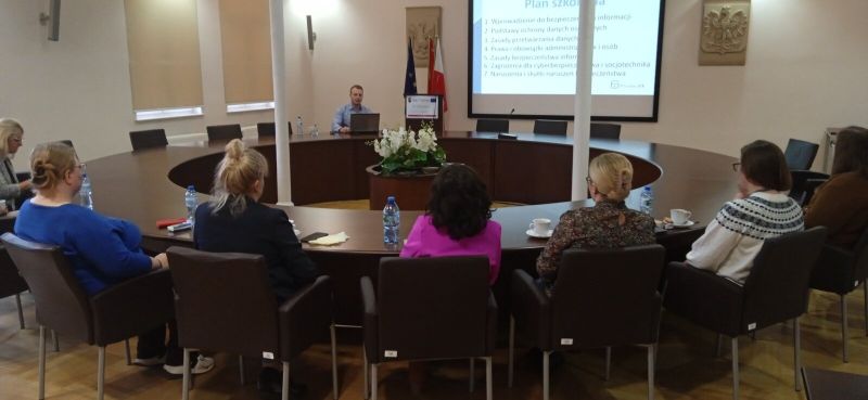 Druga grupa osób uczestnicząca w szkoleniu na miejscach siedzących przy okrągłym stole konferencyjnym