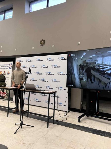 Na zdjęciu widać mężczyznę oraz film wyświetlany na telewizorze.