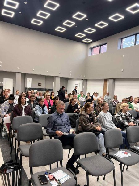 Na zdjęciu widać grupę ludzi siedzącą na krzesłach.