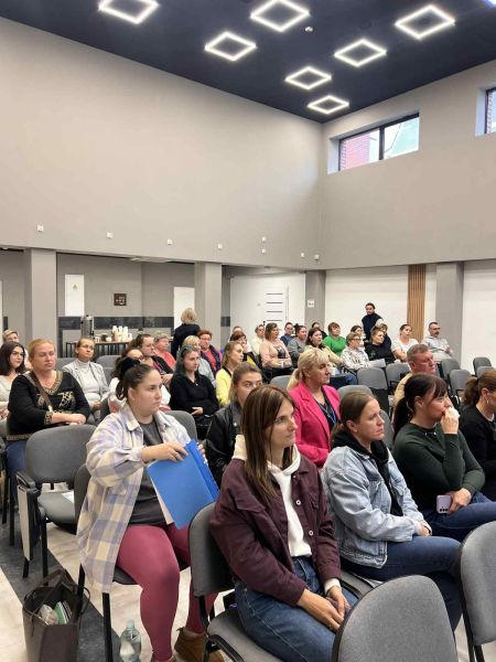 Na zdjęciu widać grupę ludzi siedzącą na krzesłach.