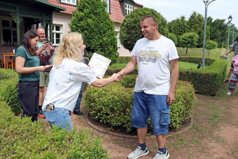 Uczestnik WTZ odbierający dyplom po zawodach wędkarskich.